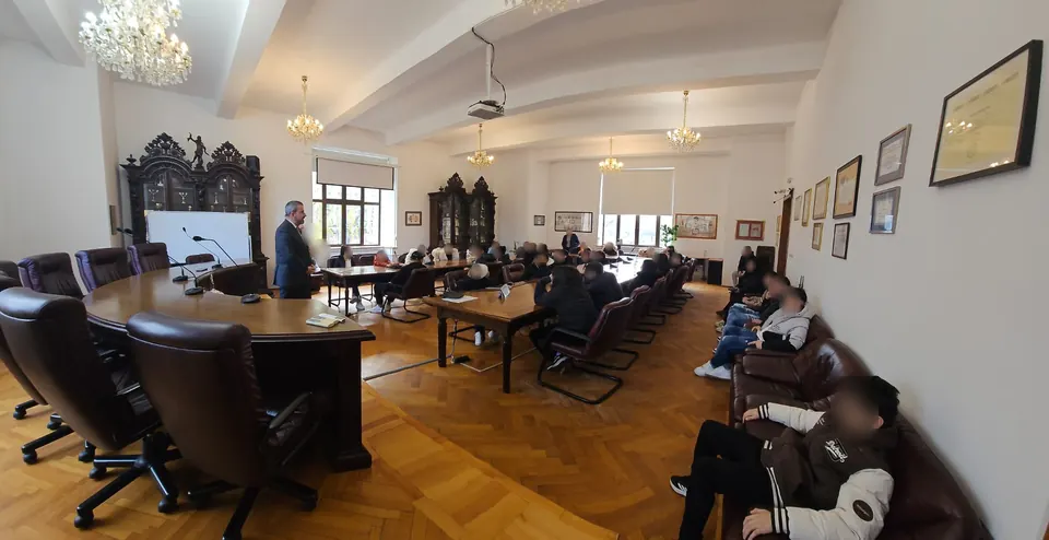 Elevi din Cernica într-o sală de consiliu a Facultății de Drept, ascultând un profesor