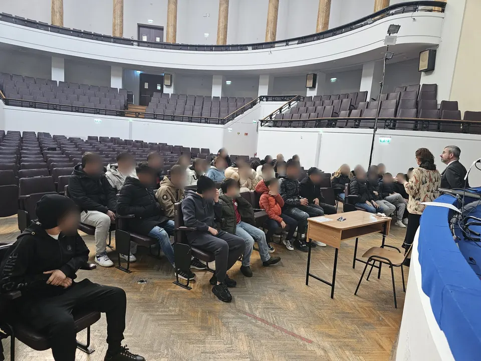 Elevi din Cernica așezați în Aula Facultății de Drept, ascultând doi profesori