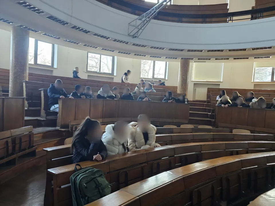Elevi în băncile de lemn ale unui amfiteatru semicircular